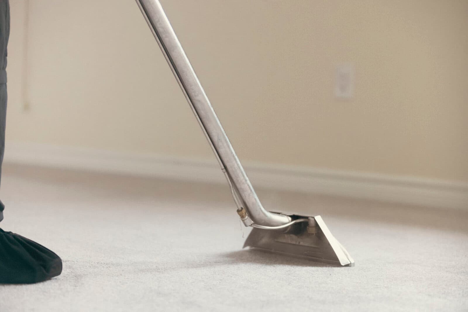 Hot-water extraction wand cleaning a cream carpet