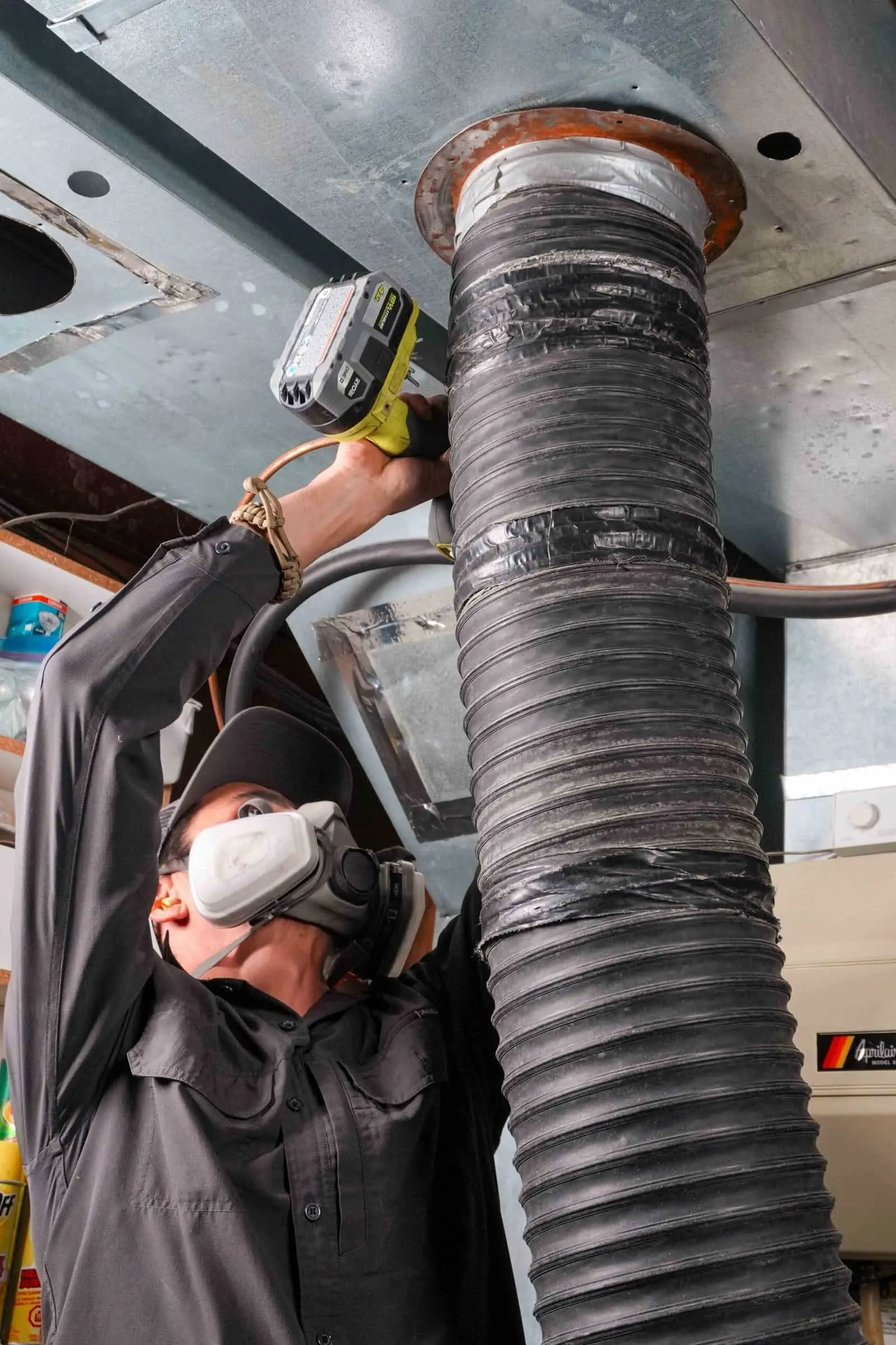Technician in a respirator working on a main duct line
