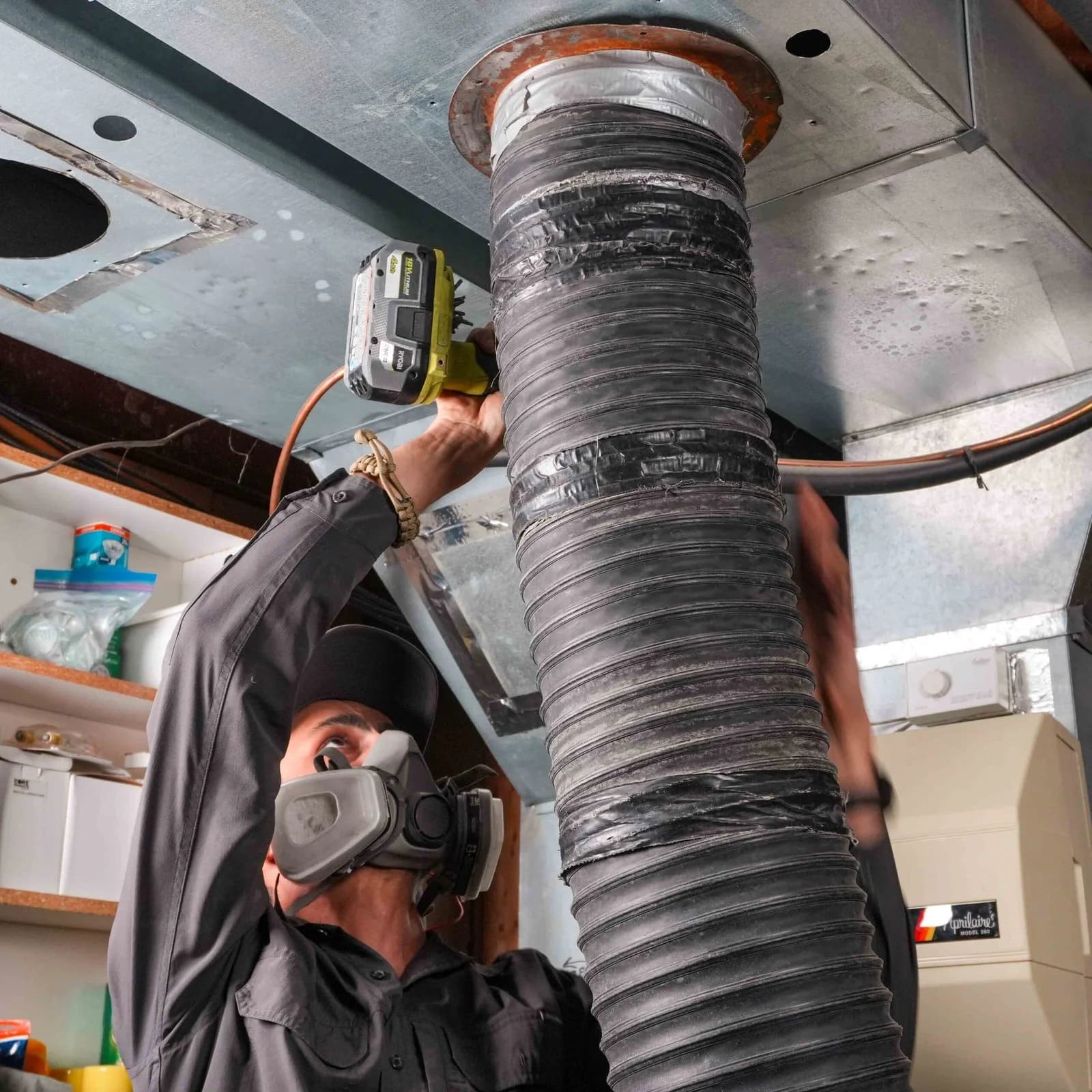 Technician connecting a vacuum hose to basement ductwork