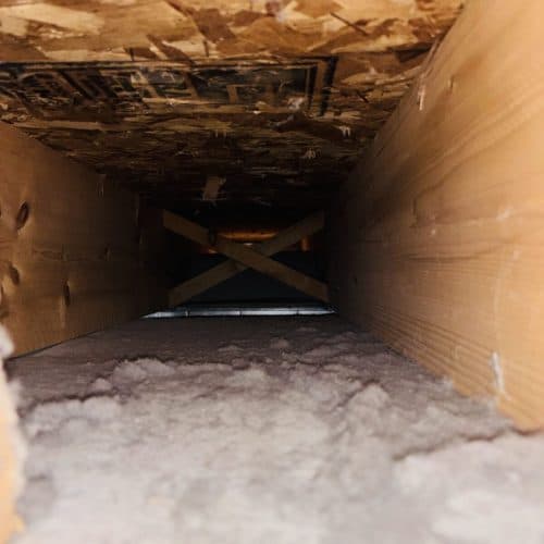 Inside of an air duct coated in dust before cleaning