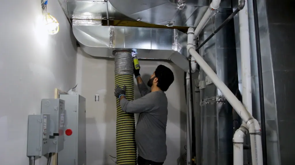 Technician attaching the vacuum line to a furnace trunk